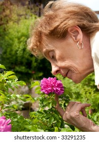 Senior Lady Smelling The Rose Of Her Garden