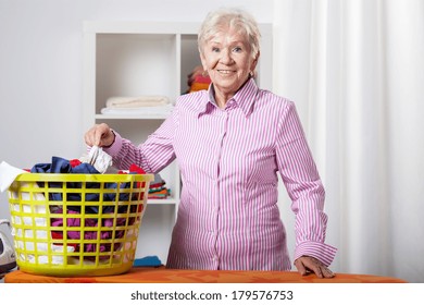 Senior lady wearing shirt during folding laundry - Powered by Shutterstock