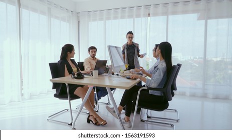 Senior leader giving advice speech to team members. Creative business people meeting at table in modern office. Multicultural business team. - Shutterstock ID 1563191593