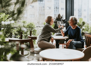 Senior lesbian couple celebrating with wine. Wine and alcohol drink concept. Senior female friends having wine at a restaurant. Two women sitting together. Diverse women. - Powered by Shutterstock