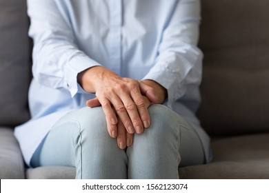 Senior lonely woman sit on couch alone with hands folded, sad elder old grandma patient clasped arms as old people health care problem, loneliness depression and social support concept close up view - Powered by Shutterstock