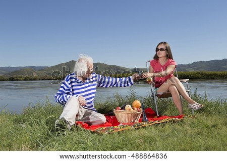Senior loving man in a striped blouse has a picnic with his girlfriend on the banks of the river