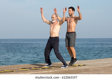 Senior Making Training On Agility Ladder With Personal Trainer