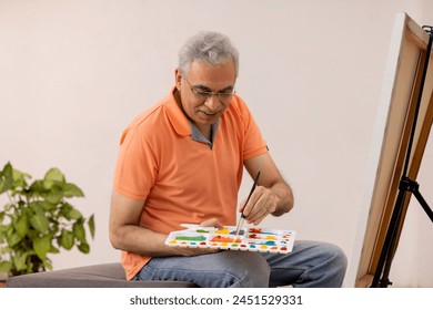 Senior male artist painting on canvas in the living room - Powered by Shutterstock