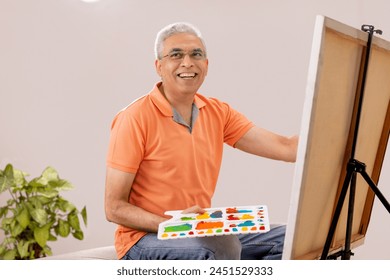 Senior male artist painting on canvas in the living room - Powered by Shutterstock