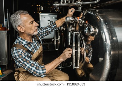 senior male brewer working with brewery equipment - Powered by Shutterstock