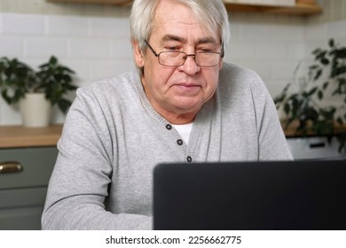 Senior male business owner in glasses sitting at desk in front of laptop. Successful older male working at home. Grey haired 60s - 70s Aged busy man typing keyboard, drinking coffee. Distance office - Shutterstock ID 2256662775