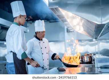 Senior male chef teaches young teenage boys cooking in school kitchen. Education Concept - Powered by Shutterstock