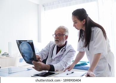 Senior Male Doctor And Asian Nurse Doing Analysis X-ray Scan Photo Patient In The Office At Hospital. Health Care Concept