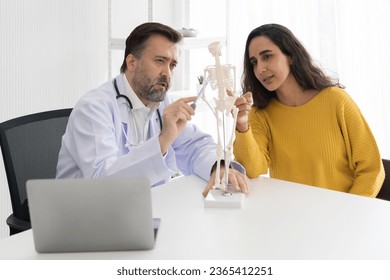 Senior male doctor and patient woman discussing together with anatomy and physiology in office at hospital