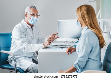 Senior Male Doctor Wear Protection Face Mask Talking With Patient In Clinic Office