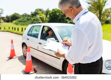 senior male driving instructor testing student driver in testing ground