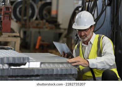 Senior male factory worker inspecting quality galvanized or metal sheet in factory. Mature male worker working checking metalwork sheet in warehouse during manufacturing process in plant - Powered by Shutterstock