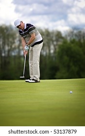 Senior male golf player putting a golf ball on the green.