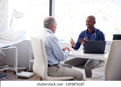 Senior Male Patient In Consultation With Doctor Sitting At Desk In Office