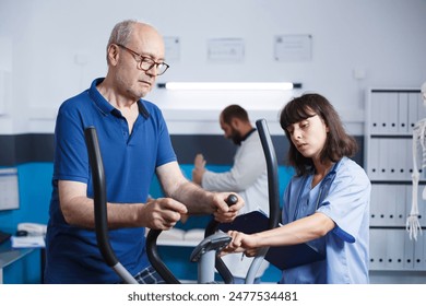 Senior male patient doing physical exercise for injury recovery with help from female nurse. Retired man using stationary bicycle to treat muscle pain with physiotherapy at rehabilitation clinic. - Powered by Shutterstock