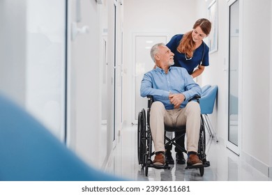 Senior male patient sitting in wheelchair in hospital corridor with female nurse doctor. Caregiver medical worker supporting disabled immobile patient in hospice - Powered by Shutterstock