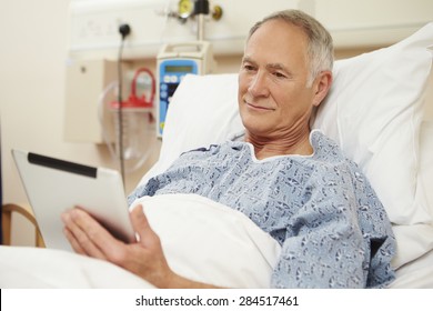 Senior Male Patient Using Digital Tablet In Hospital Bed