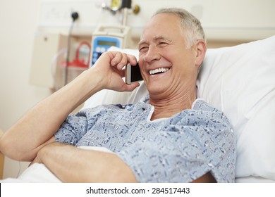 Senior Male Patient Using Mobile Phone In Hospital Bed