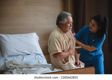 Senior Male Patient Wearing Gown Admitted In Hospital Holding Chest Due To Pain Suffering From Heart Attack While Holding And Taking Support Of Window In Ward And Private Room