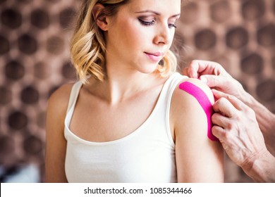 Senior male physiotherapist applying tape on a female patient. Close up. - Powered by Shutterstock