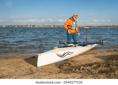 Senior male rower with his rowing shell on a beach of Boyd Lake in northern Colorado, early spring scenery - Powered by Shutterstock