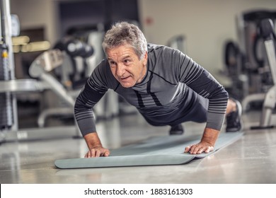 Senior male stays fit by doing pushups on a mat inside the fitness center. - Powered by Shutterstock