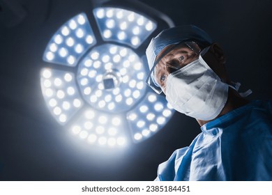 Senior male surgeon at work on operating in hospital. Concentrated surgeon performing operation surgery, looking at the table with patient. Sterile medical theater - Powered by Shutterstock