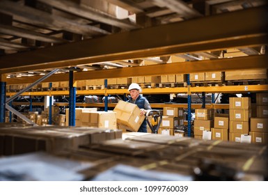 Senior Male Warehouse Worker Or A Supervisor Unloading A Pallet Truck With Boxes.