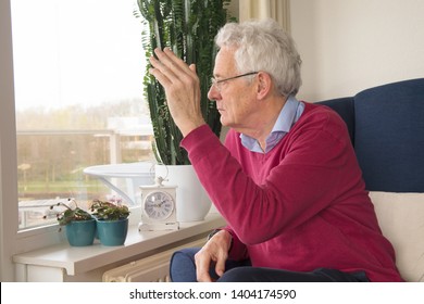 Senior Man Alone Sitting In Chair And Waving Goodbye To Somebody Outside