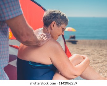 A Senior Man Is Applying Sun Cream To His Wife's Back