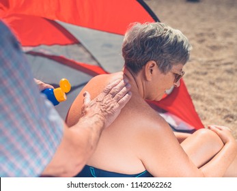 A Senior Man Is Applying Sun Cream To His Wife's Back