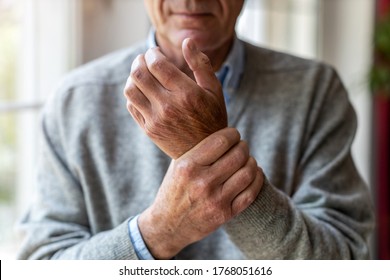 Senior man with arthritis rubbing hands
