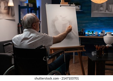 Senior man artist using wheelchair drawing original pencil drawing still life vase feeling creative easel in home studio  Retired art teacher who is paralyzed creating authentic design sketch 