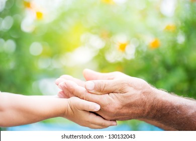 Senior Man And Baby Holding Empty Hands Against Green Spring Background