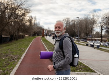 Senior man with backpack and yoga mat walking on training  outdoors, healthy lifestyle concept - Powered by Shutterstock