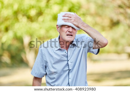 Senior man with bad circulation cools his head with wet cloth