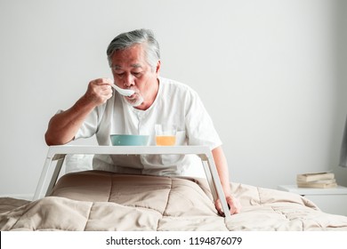 Senior Man In Bed Enjoying Breakfast. Old Asian Male With White Beard Eating Congee And Orange Juice. Senior Home Service Concept.