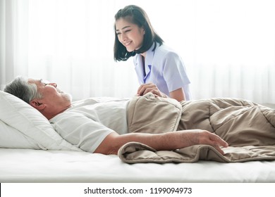 Senior man in bed and nurse woke him up. Old asian man and beautiful asian nurse woman in bedroom and open curtain. Senior home service concept. Close up shot.