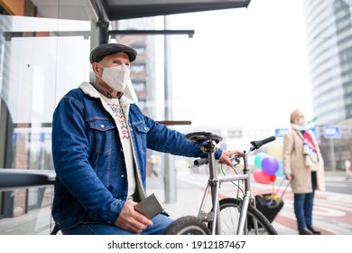 Senior man with bicycle and smartphone outdoors on bus stop in city, coronavirus concept. - Powered by Shutterstock