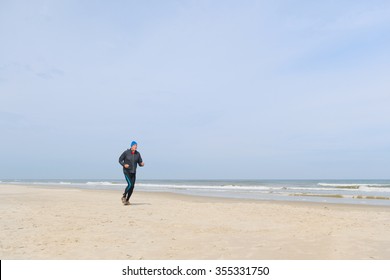 Senior Man In Black Clothes Running At The Beach