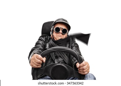 Senior Man In Black Leather Jacket And Goggles Driving Very Fast Seated On A Car Seat Isolated On White Background