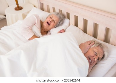 Senior Man Blocking Out His Wifes Snoring At Home In Bedroom
