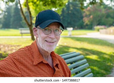 A Senior Man In Blue Baseball Cap And Orange Shirt, Portrait