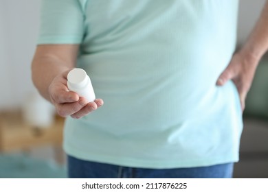 Senior Man With Bottle Of Pills Suffering From Back Pain At Home, Closeup