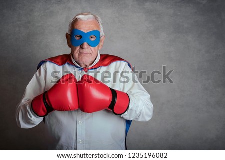 senior man with boxing gloves on gray background