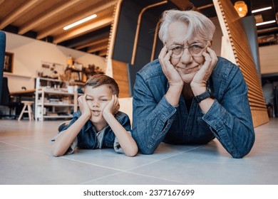 Стоковая фотография: Senior man and boy leaning on elbows lying down at home