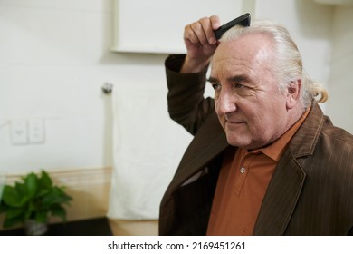 Senior Man Brushing Hair In Front Of Bathroom Mirror When Getting Ready For Romantic Date