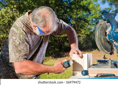 Senior Man Building A Birdhouse Using A Pneumatic Nail Gun.