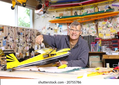 Senior Man Building Model Airplane In Workshop